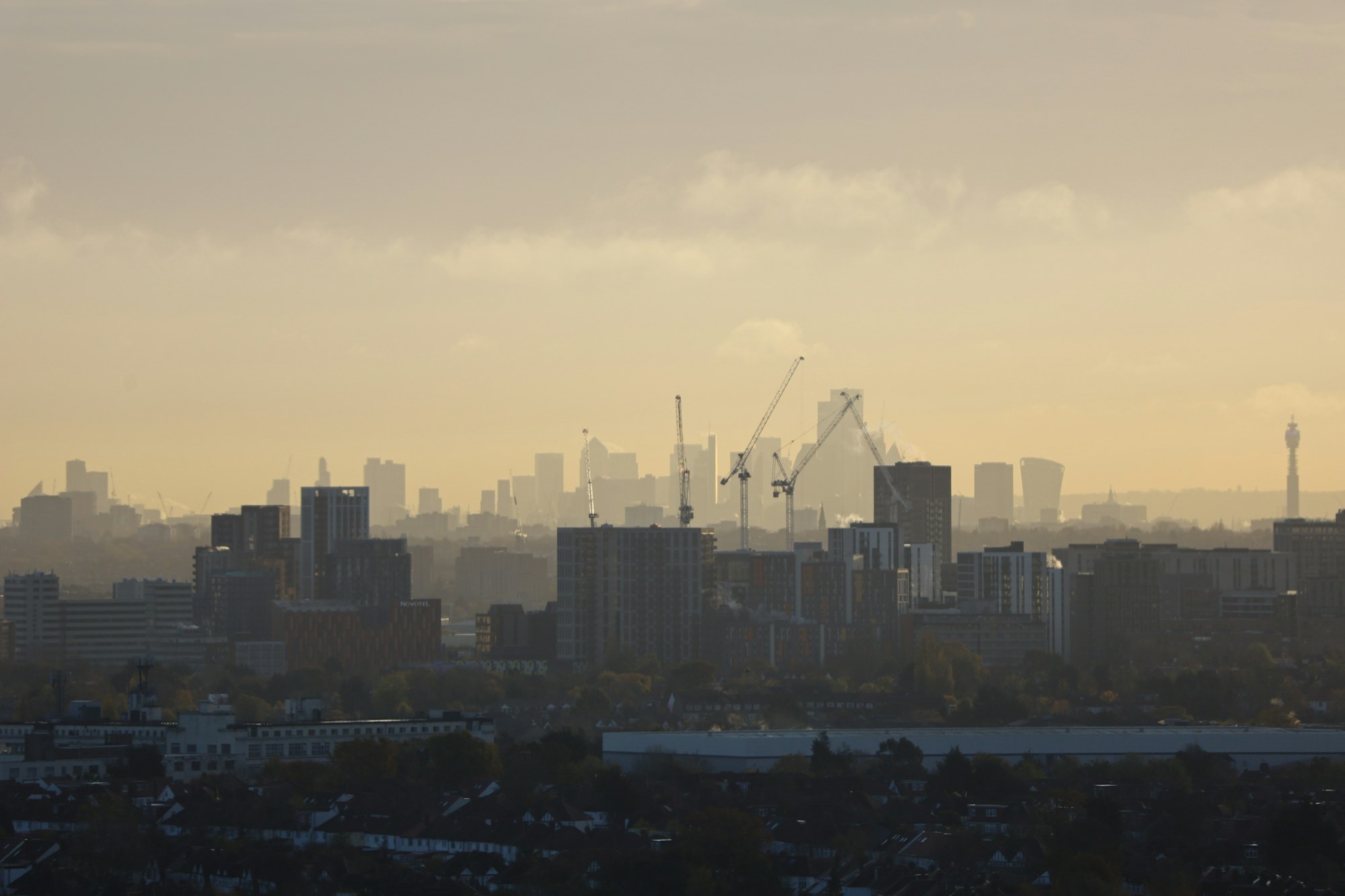 London skyline at golden hour with construction cranes across the city